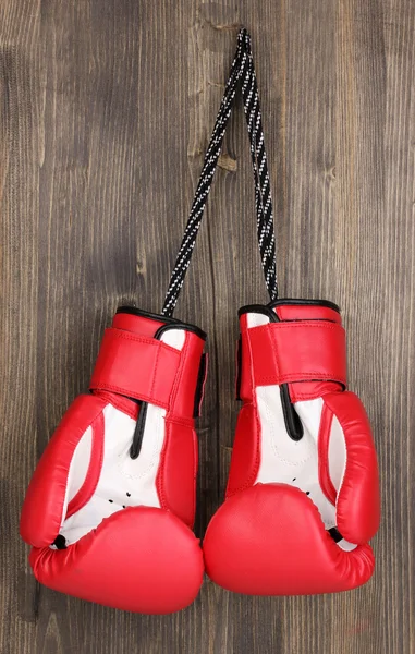 木製の背景に掛かっている赤いボクシング用グローブ — ストック写真