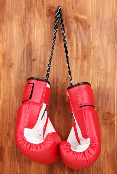 Gants de boxe rouge suspendus sur fond en bois — Photo