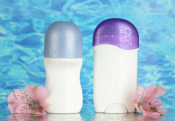 Deodorants with flowers on blue sea background — Stock Photo, Image