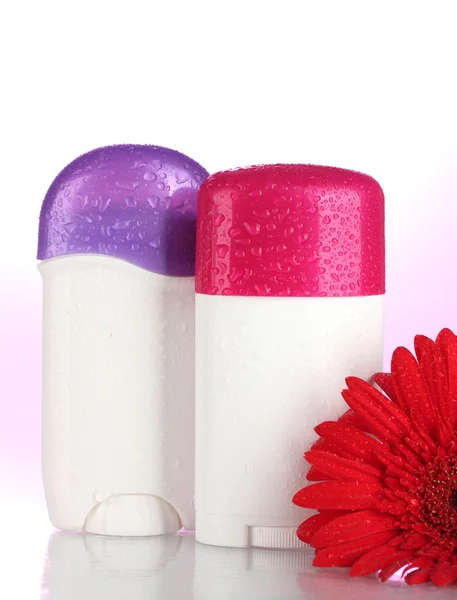 Дезодоранты с цветами на розовом фоне — стоковое фото
