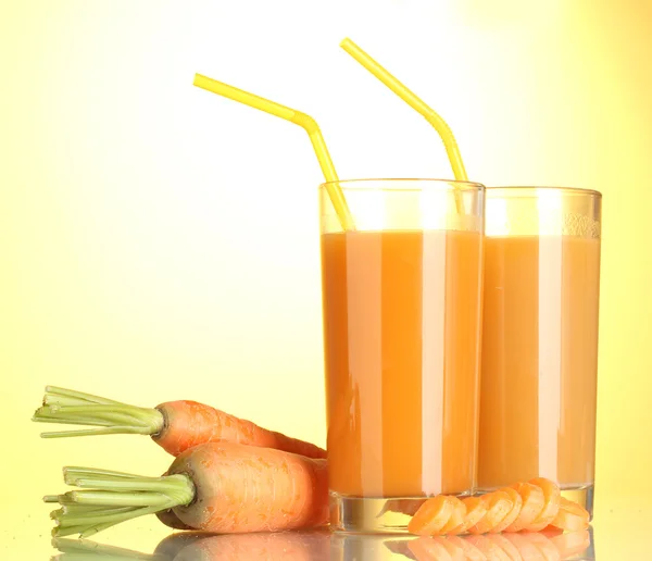 Bicchieri di succo di carota su sfondo giallo — Foto Stock