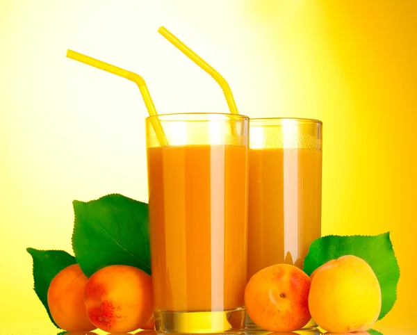 Glasses of apricot juice on yellow background — Stock Photo, Image