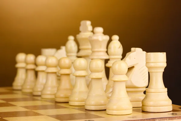 Schackbräde med schackpjäser på brun bakgrund — Stockfoto