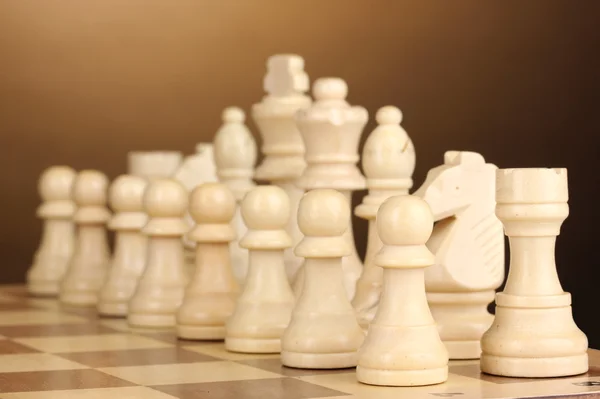 Tablero de ajedrez con piezas de ajedrez sobre fondo marrón — Foto de Stock