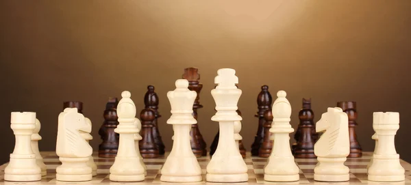 Tablero de ajedrez con piezas de ajedrez sobre fondo marrón —  Fotos de Stock