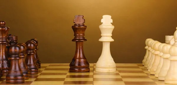 Schachbrett mit Schachfiguren auf braunem Hintergrund — Stockfoto