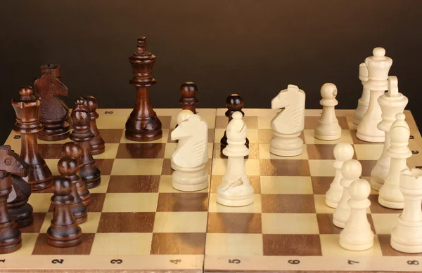 茶色の背景にチェスの駒でチェス盤 — ストック写真