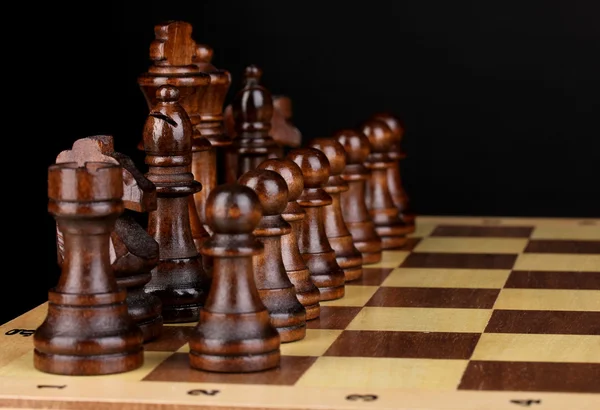 Schackbräde med schackpjäser isolerade på svart — Stockfoto
