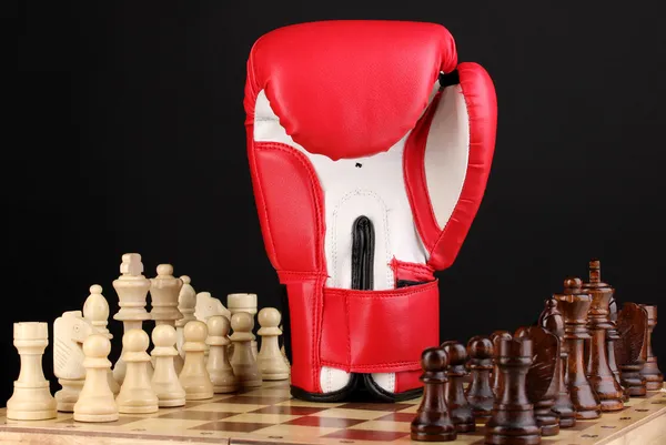 Tábua de xadrez e luva de boxe isolada em preto — Fotografia de Stock