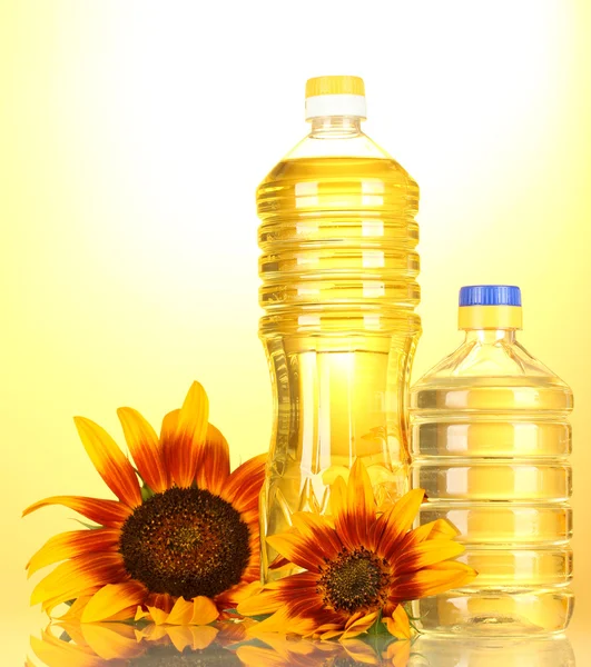Olej słonecznikowy i słoneczniki na żółtym tle — Zdjęcie stockowe
