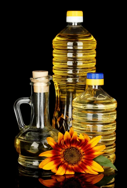 Sonnenblumenöl in Plastikflaschen und kleinen Karaffen isoliert auf schwarzem Hintergrund — Stockfoto