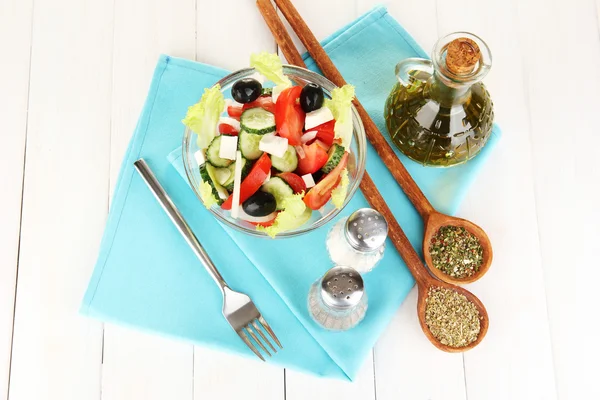 Ízletes görög saláta, fűszerek, fehér fa háttér — Stock Fotó