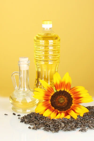 Slunečnicový olej v plastové lahvi a malou karafu na žlutém podkladu — Stock fotografie