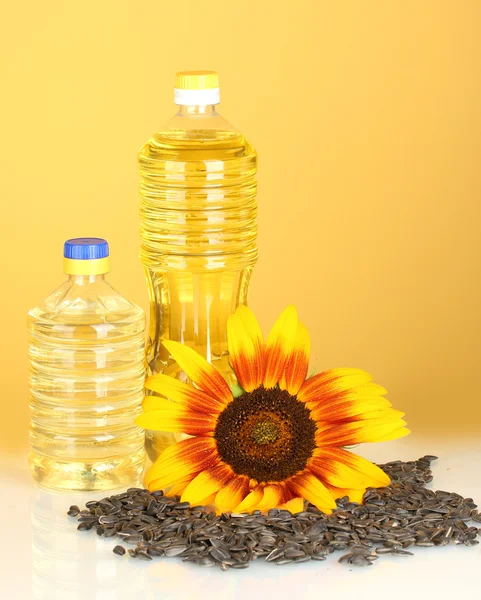 Подсолнечное масло в пластиковых бутылках на желтом фоне — стоковое фото