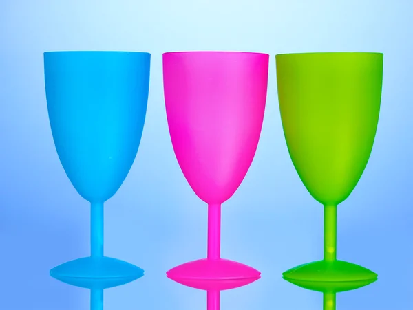 Luminosas copas de plástico sobre fondo azul — Foto de Stock