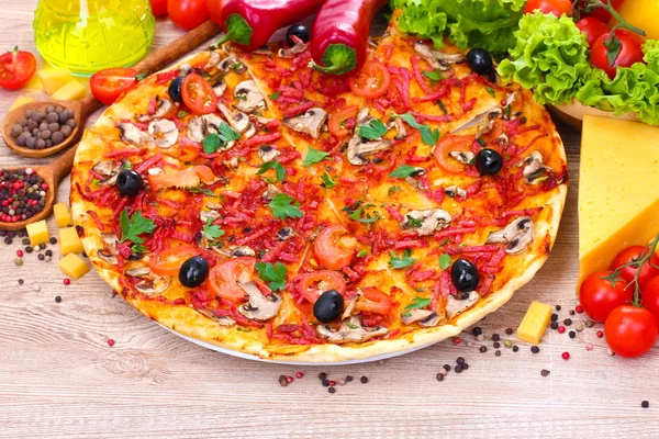 Läcker pizza och grönsaker på träbord — Stockfoto