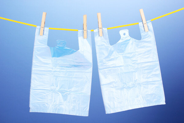 Целофановые мешки висят на веревке на синем фоне
