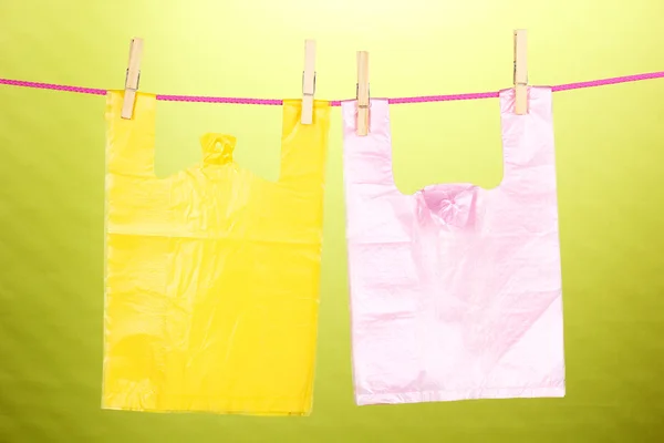 Cellophane bags hanging on rope on green background — Stock Photo, Image