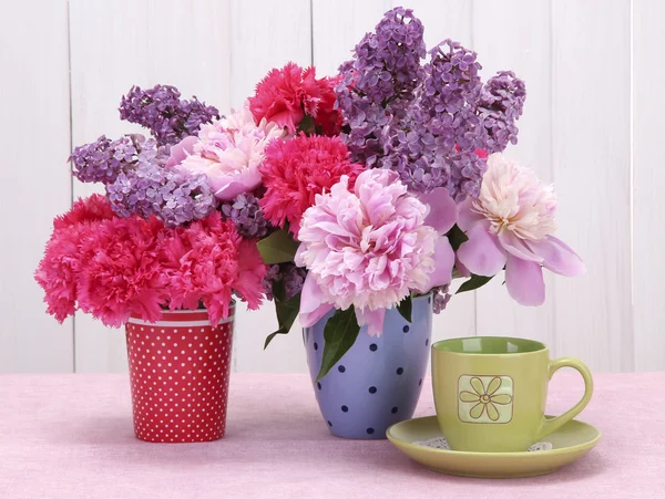 Vårblommor och cup på bordet på vit trä bakgrund — Stockfoto