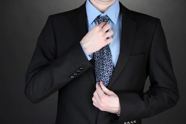 黒の背景にネクタイを修正する実業家 — ストック写真
