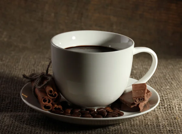 Чашка кави, квасолі та шоколаду на мішкуватому фоні — стокове фото