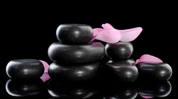 Pietre termali e petali di rosa su sfondo nero — Foto Stock
