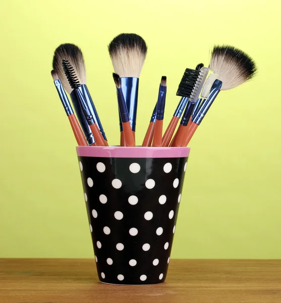 Makeup brushes in a black polka-dot cup on yellow background — Stock Photo, Image