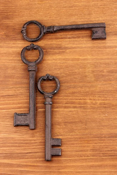 Três chaves antigas no fundo de madeira — Fotografia de Stock