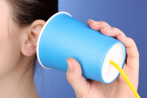 Menselijk oor en papier cup in de buurt van het close-up op blauwe achtergrond — Stockfoto