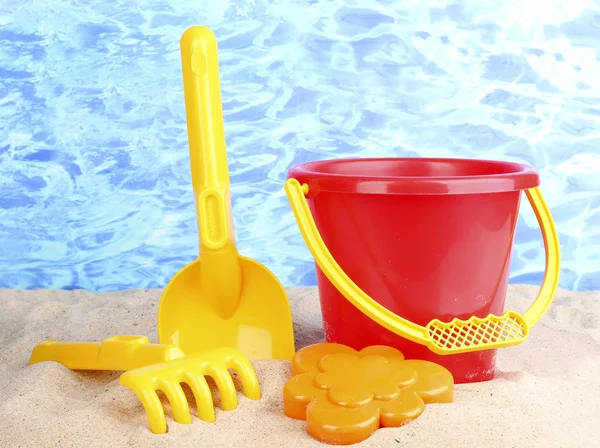 Children's beach toys on sand on water background — Stock Photo, Image