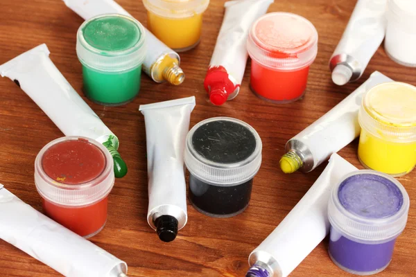 Tubos com aquarelas coloridas e frascos com guache na mesa de madeira close-up — Fotografia de Stock