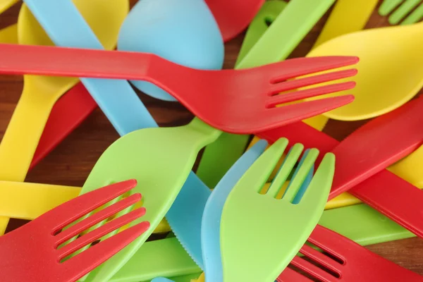 Bright plastic disposable tableware on wooden background close-up