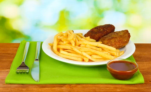 Kartoffeln Pommes mit Burgern auf dem Teller auf grünem Hintergrund Nahaufnahme — Stockfoto