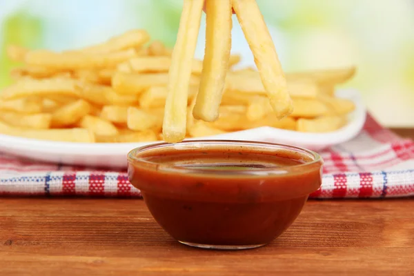 Pommes de terre frites dans l'assiette avec sauce sur fond bois close-up — Photo