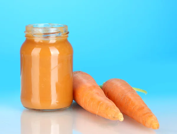 Glas mit Karotten Babynahrung auf buntem Hintergrund — Stockfoto