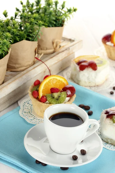 Taza de café y pasteles dulces con frutas en la mesa de madera —  Fotos de Stock