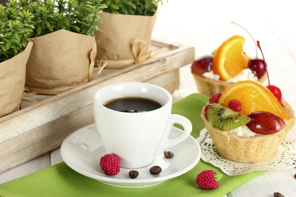 Xícara de café e bolos doces com frutas na mesa de madeira — Fotografia de Stock