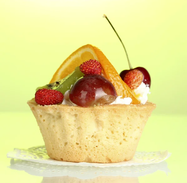 Süße Torte mit Früchten auf grünem Hintergrund — Stockfoto