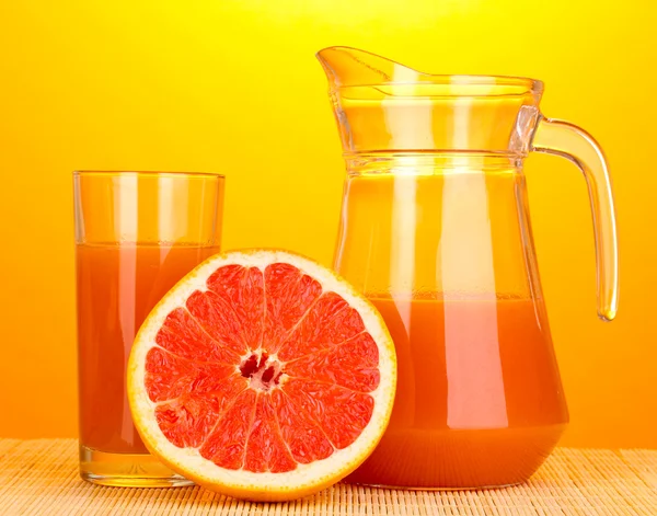 Grapefruit juice and grapefruit on bamboo mat on yellow background — Stock Photo, Image