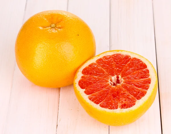 Ripe grapefruit and half on wooden background — Stock Photo, Image