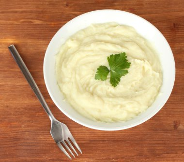 Mashed potato with parsley in the bowl on wooden background close-up clipart