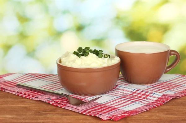 Mashed potato in the bowl and cup with milk on colorful napkin on wooden background — Stock Photo, Image