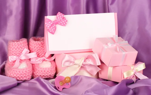 Buty dla dzieci różowy, pacifierd, pocztówka i prezenty na tle jedwab — Zdjęcie stockowe
