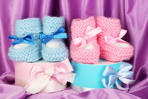 Rosa und blaue Babystiefel und Geschenke auf Seidenhintergrund — Stockfoto