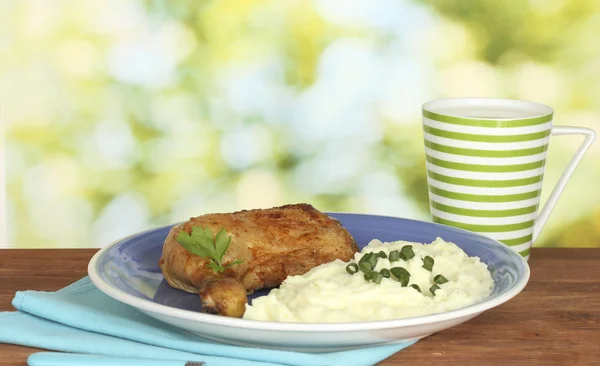 Coscia di pollo arrosto con purè di patate nel piatto e tazza con latte sul tavolo di legno su sfondo luminoso primo piano — Foto Stock