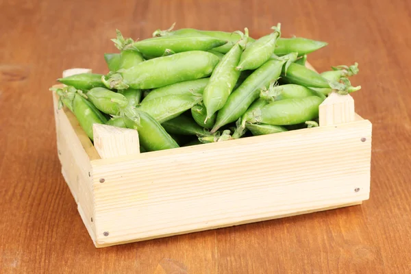 Green peas in crate on wooden background — Stock Photo, Image