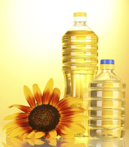 Sunflower oil and sunflowers on yellow background — Stock Photo, Image
