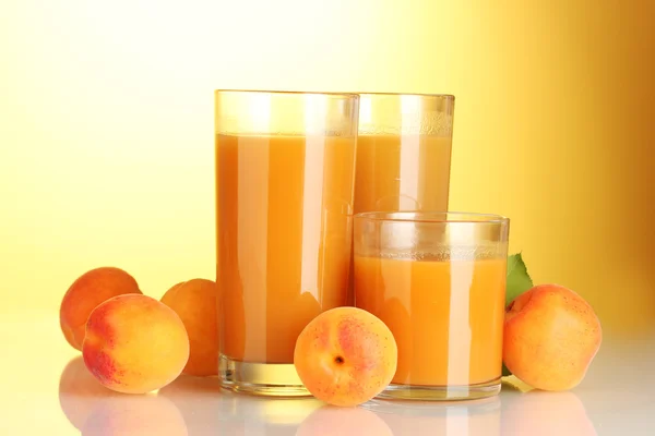 Glasögon av aprikos juice på gul bakgrund — Stockfoto