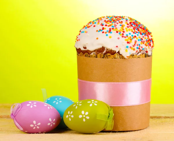 Beautiful Easter cake with eggs on wooden table on green background — Stock Photo, Image