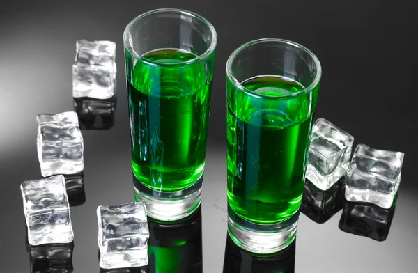 Dvě sklenice absintu a ledu na šedém pozadí — Stock fotografie